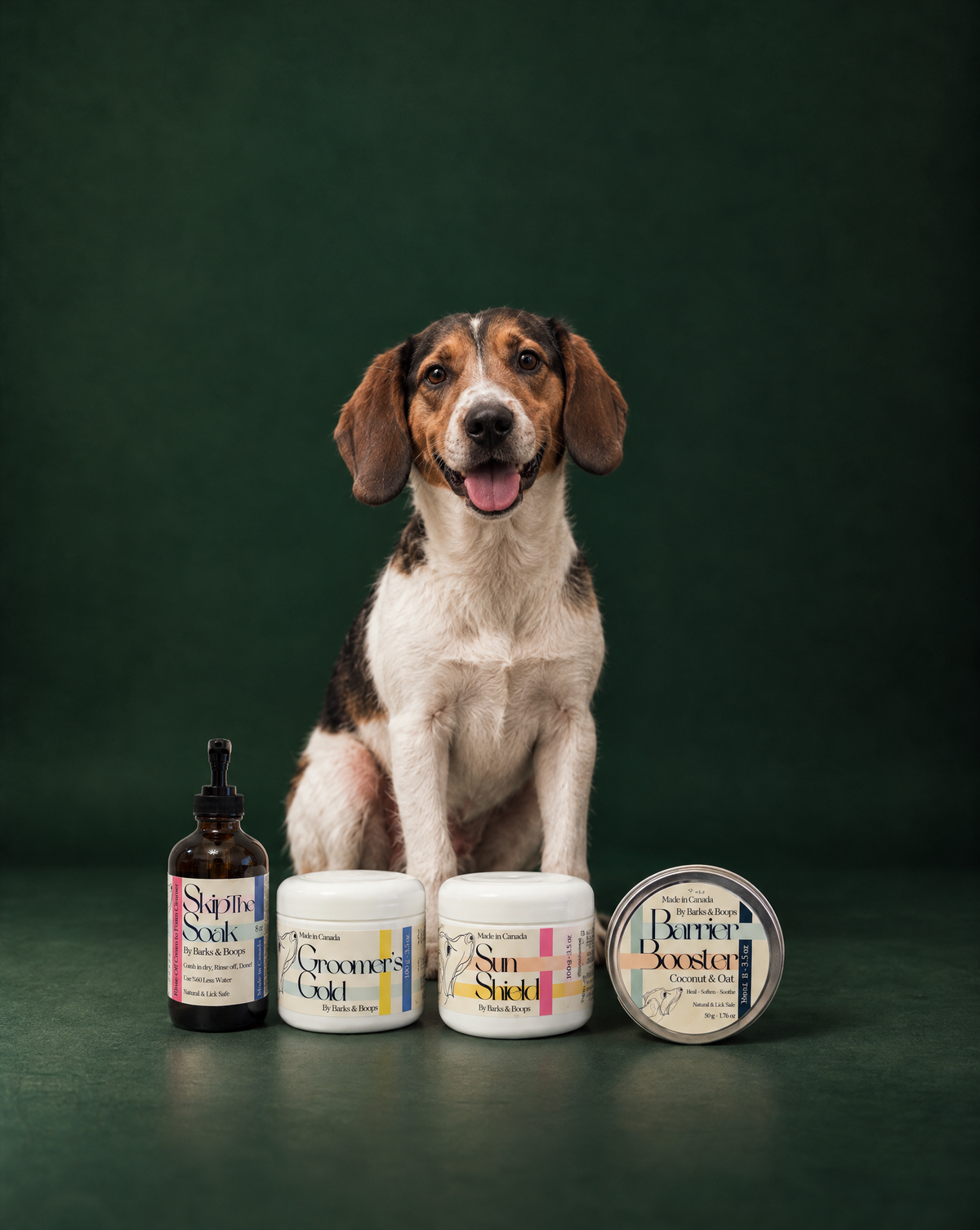 Charlie smiling behind a lineup of Barks & Boops dog skincare products.